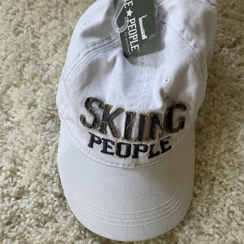 NWT. White baseball cap. Adjustable. Skiing people.